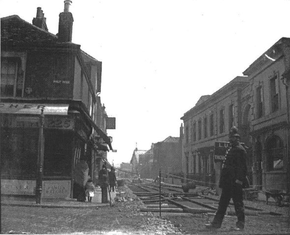 No. 225 on the corner of Half Acre and the High Street, the road is dug up for laying of the new tramlines. A Police Constable is in the foreground.