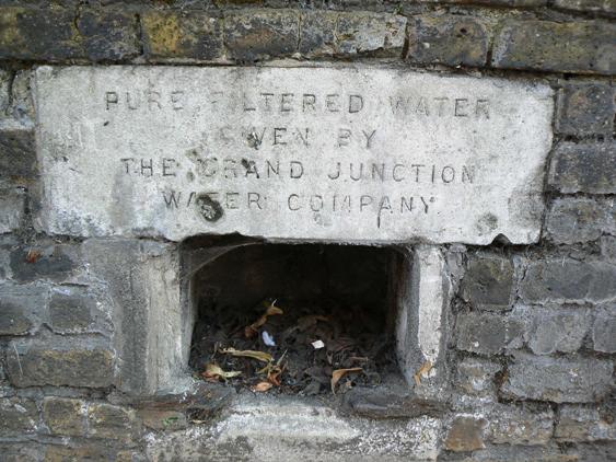 Recess in stone wall with plaque above 'Pure filtered water given by the Grand Junction Water Company'
