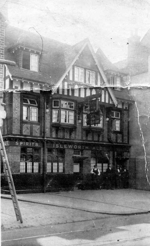 Magpie & Crown PH, on a corner, three floors; timber frame and brick infill on the first floor, timber frame white plaster on top floor, tiled roof; a small group of men are outside