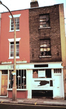 Two 3-storey brick-built terrace properties, the left is in reasonable condition, the right has broken windows and appears derelict