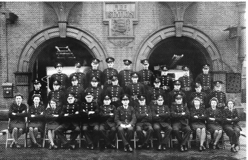 Formal photo of 32 firemen and women outside Brentford Fire Station, 2 fire engines just visible