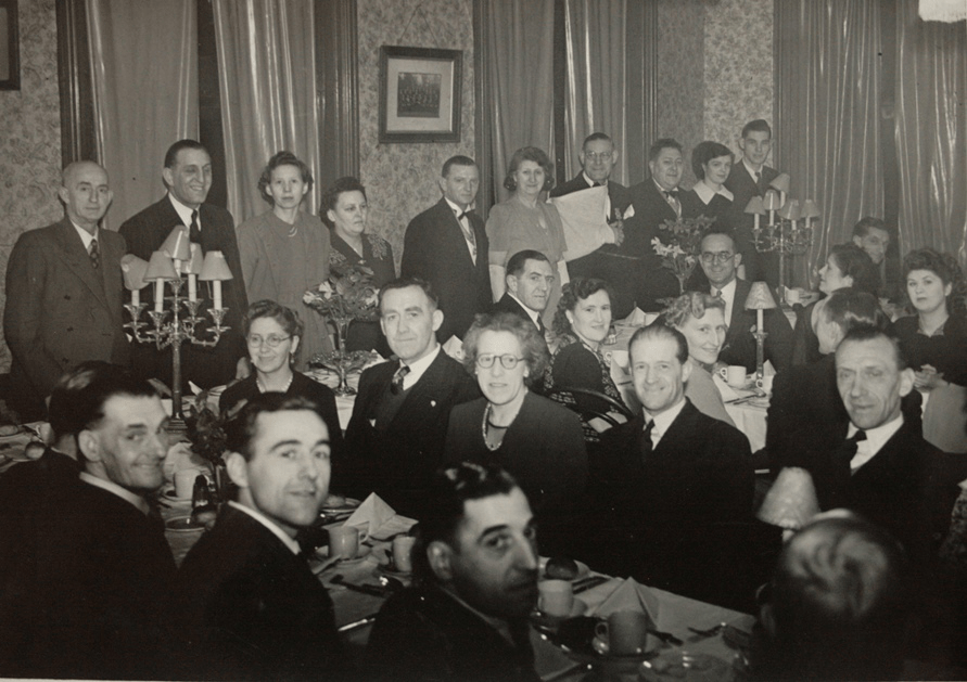 Around 25 people, men and wives, aged 30 - 60ish in a pub dining room